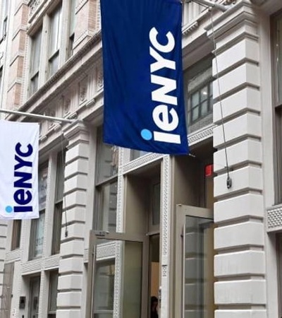 A street view of a building with flags displaying the logo of 'ieNYC'.